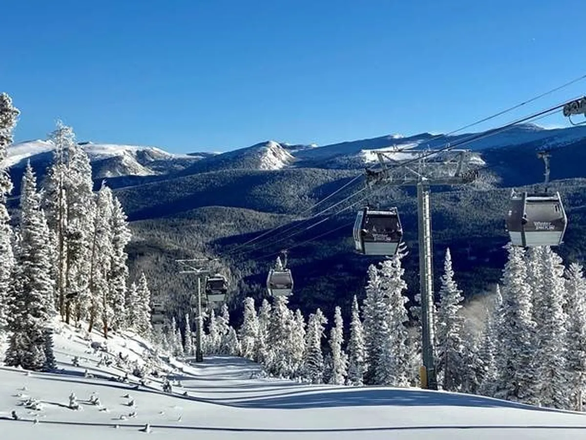 A stunning winter scene featuring ski lift gondolas gliding over snow-covered trees, with a dramatic mountain backdrop. The image exudes both exhilaration and serenity, capturing the essence of winter sports and scenic beauty.